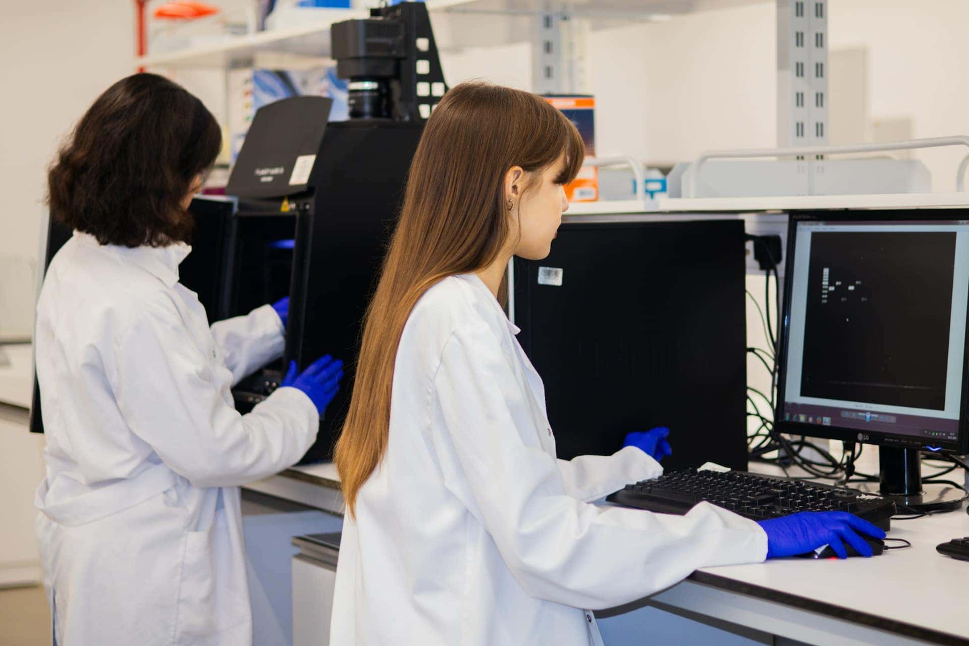 Duas pesquisadoras trabalham em computadores num laboratório contemporâneo