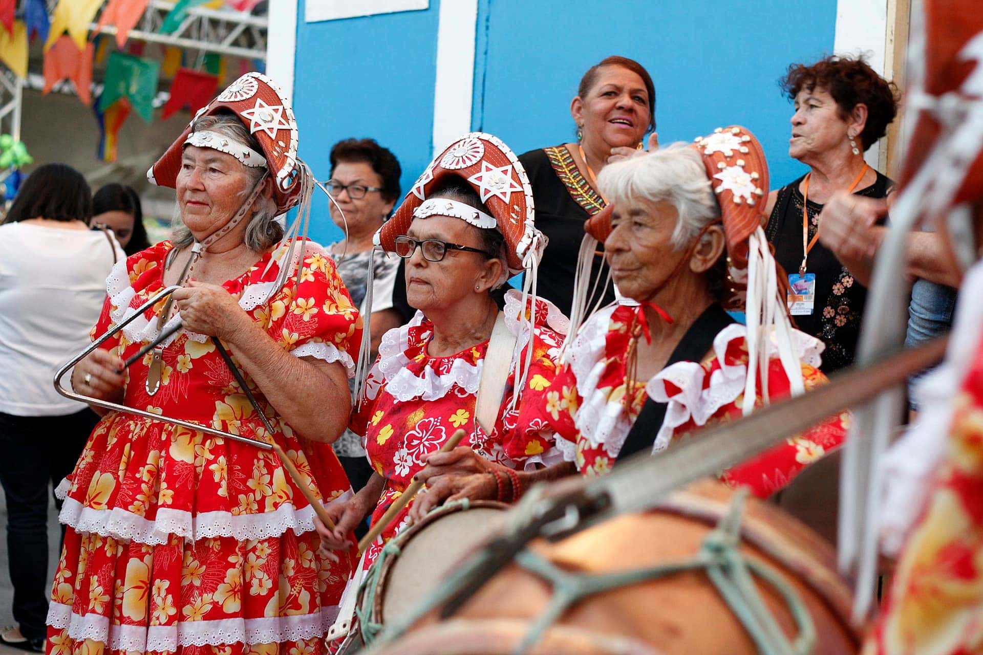 Músicos com trajes de festa junina tocam sanfona, zabumba e triângulo numa apresentação em Caruaru