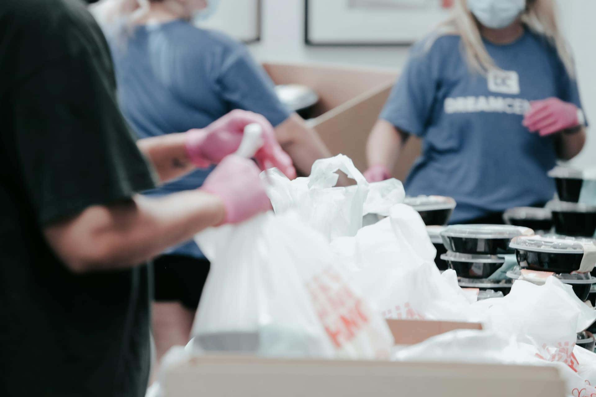 Voluntários de camiseta azul montam sacolas de alimentos para doação